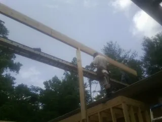 Carpenter setting a ridge beam over a new addition frame — Ice Dam Removal by Roofing Brothers in Boerne
