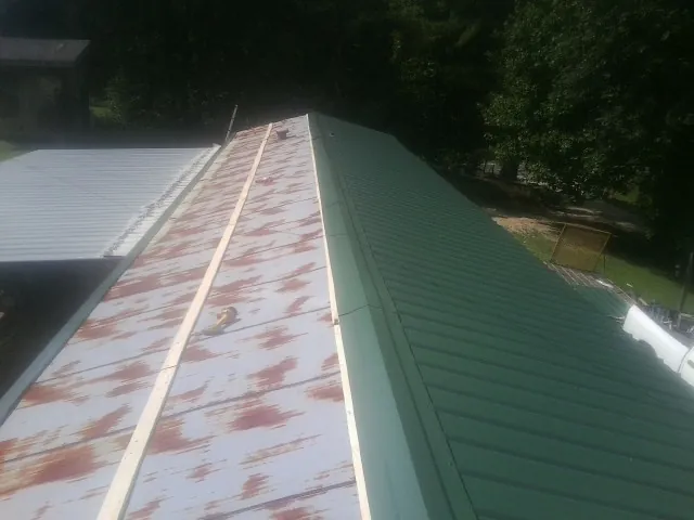 Old rusted panels beside newly installed green metal roofing — Wind Damage Roof Repair by Roofing Brothers in Boerne