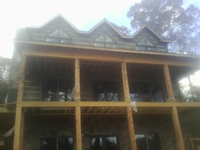 Dormers and porch framing on a large log home under construction — Roof Coating work by our crew in Boerne