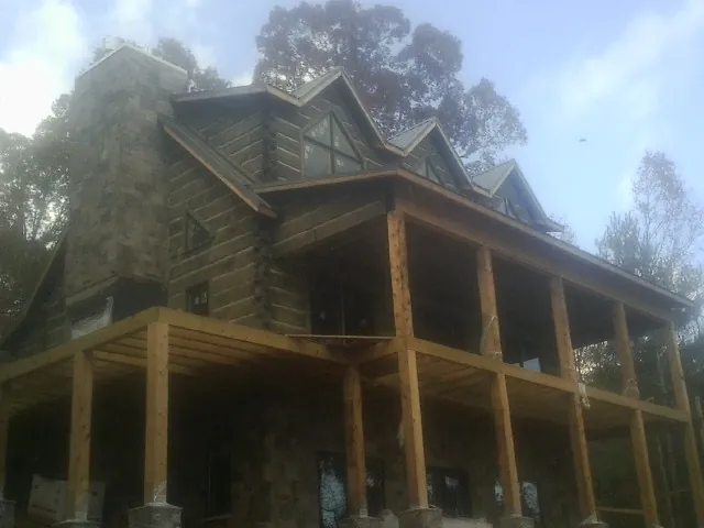 Stone chimney and dormers on a large log home with a timber porch in Boerne