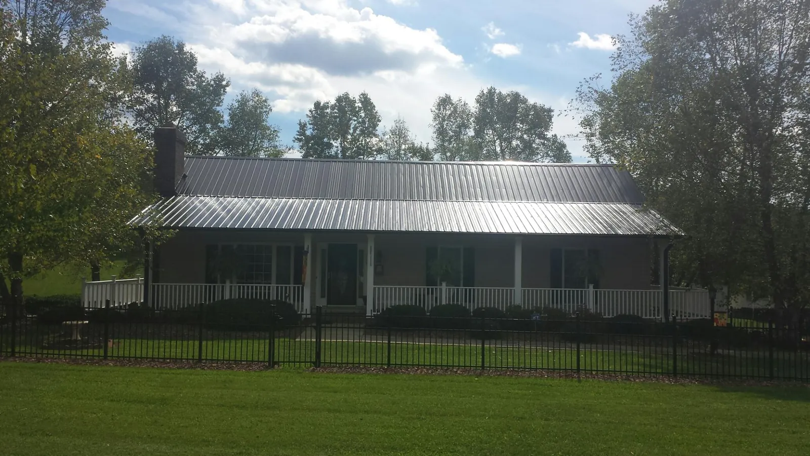 Gray metal roof on a brick ranch with a full width front porch — Gutter Guard Installation work by our crew in Boerne