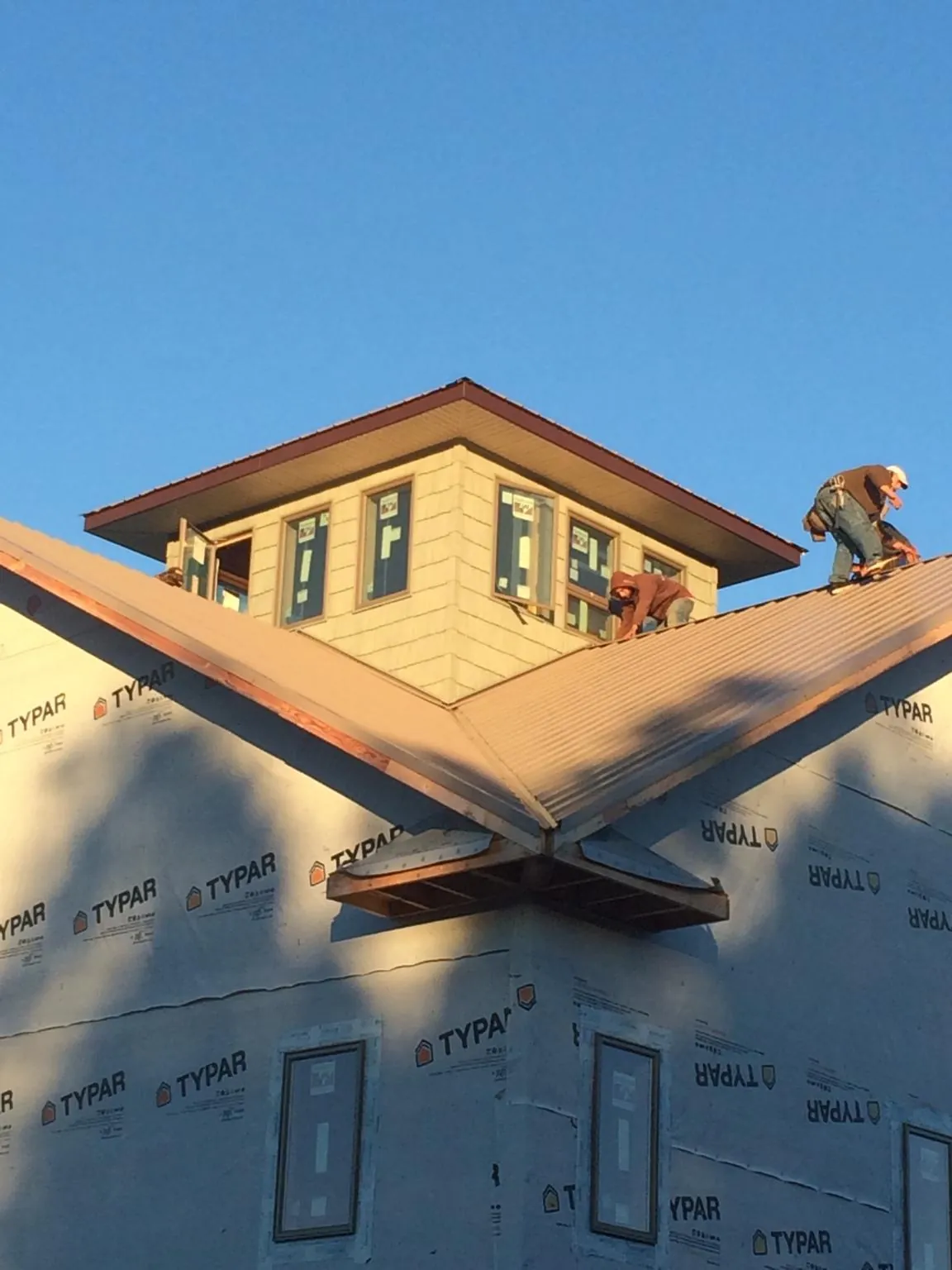 Roofers working around a rooftop cupola on a new metal roof at sunset — Roof Waterproofing in Boerne by Roofing Brothers